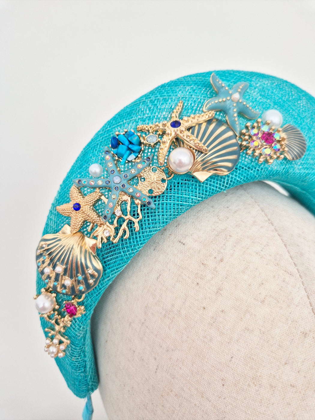 Turquoise headband with gold and blue embellishments on a mannequin head close up