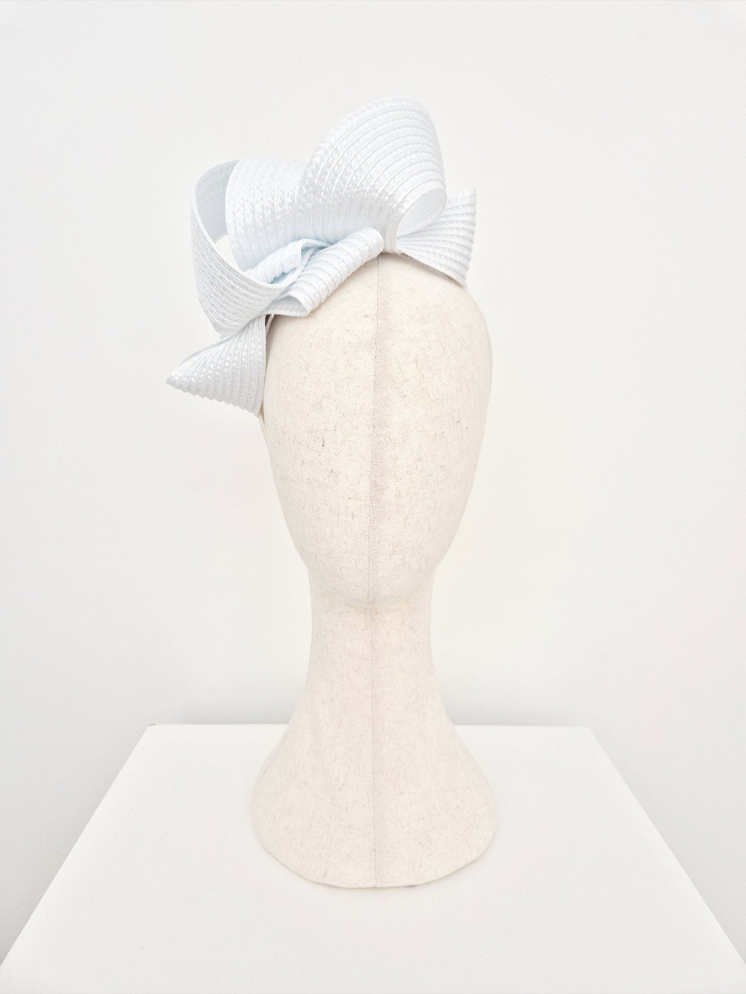 White  loop fascinator on a mannequin head against a white background