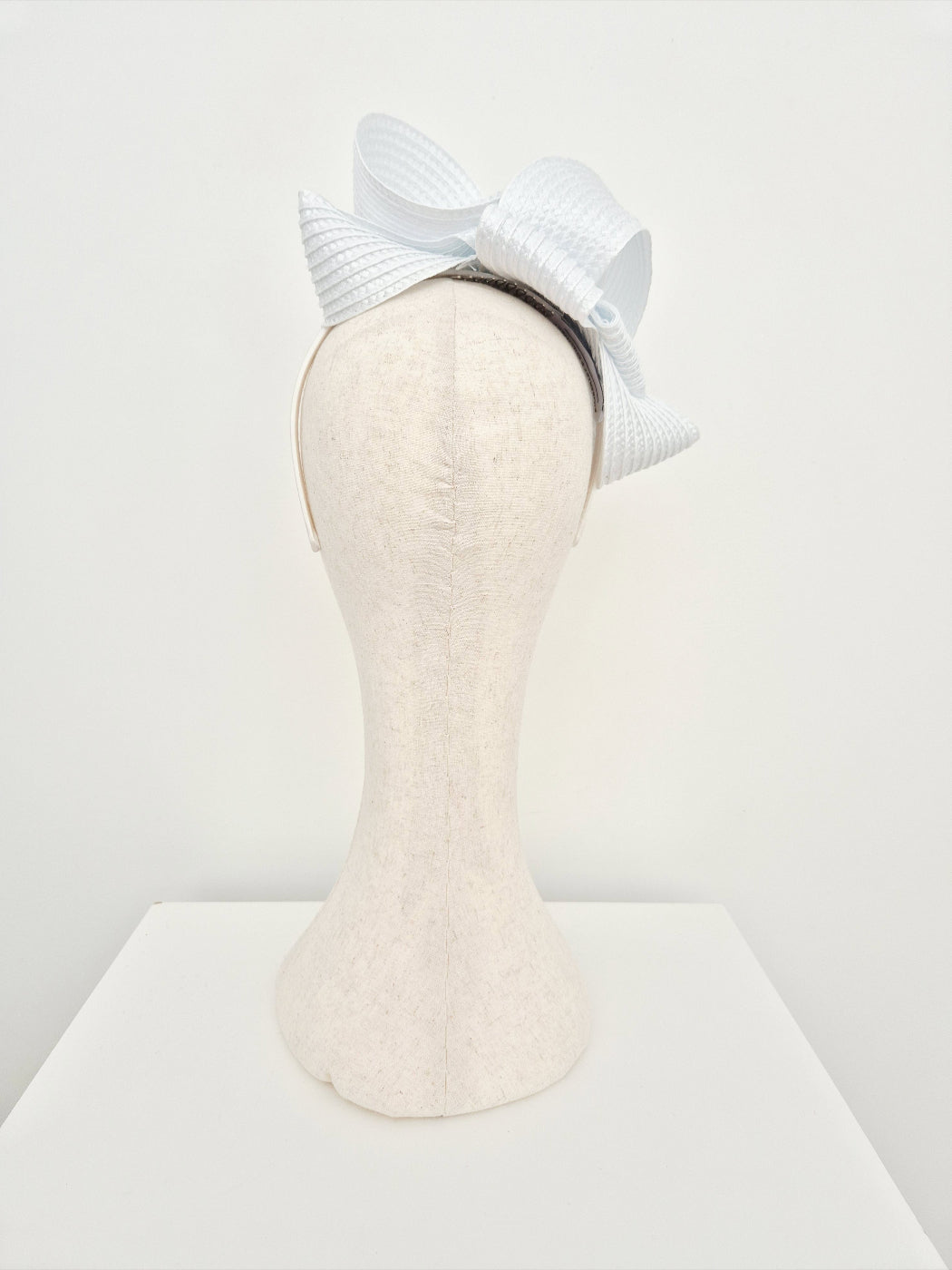White loop headpiece on a mannequin head against a light gray background
