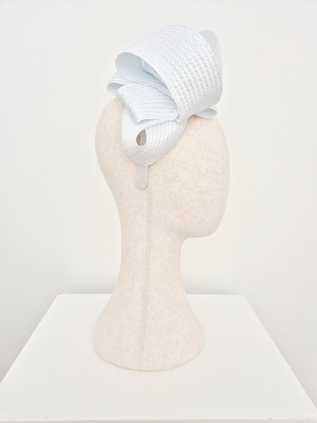 White loop headband on a mannequin head against a white background side view