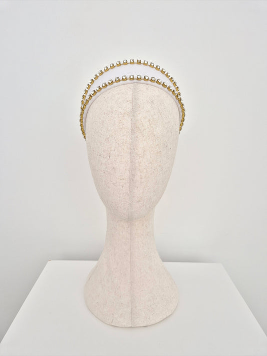 white velvet headband with gold set rhinestone trim on a mannequin head against a white background