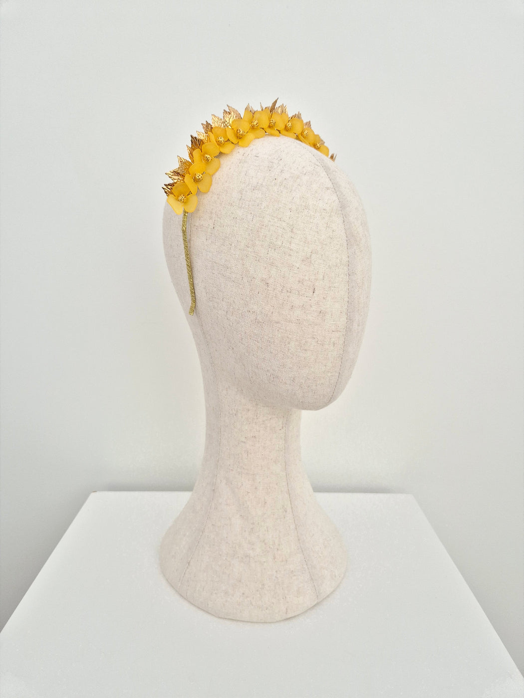 Yellow flower headband on a mannequin head against a white background side view