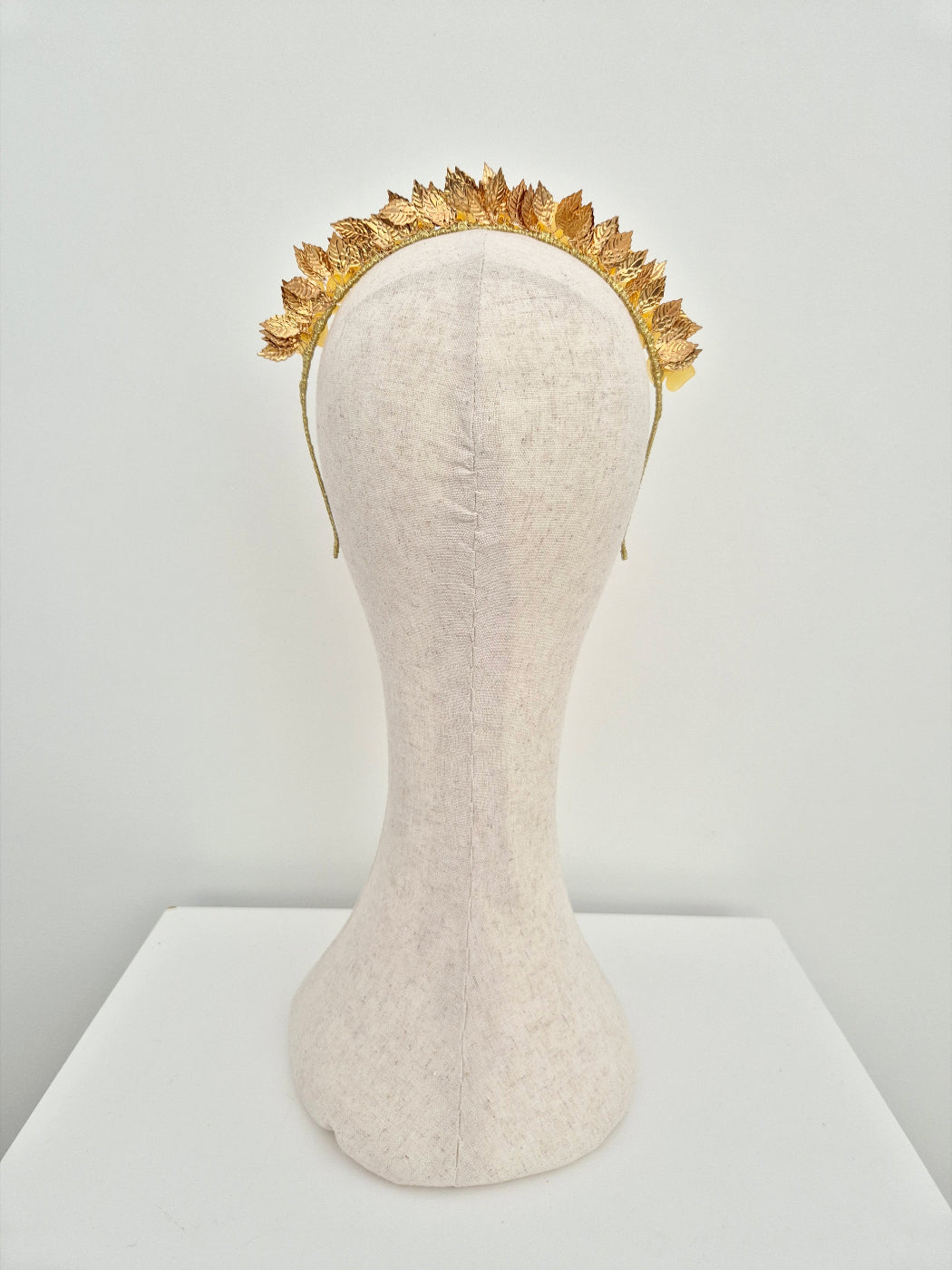Gold leaf headband on a mannequin head against a white background back view