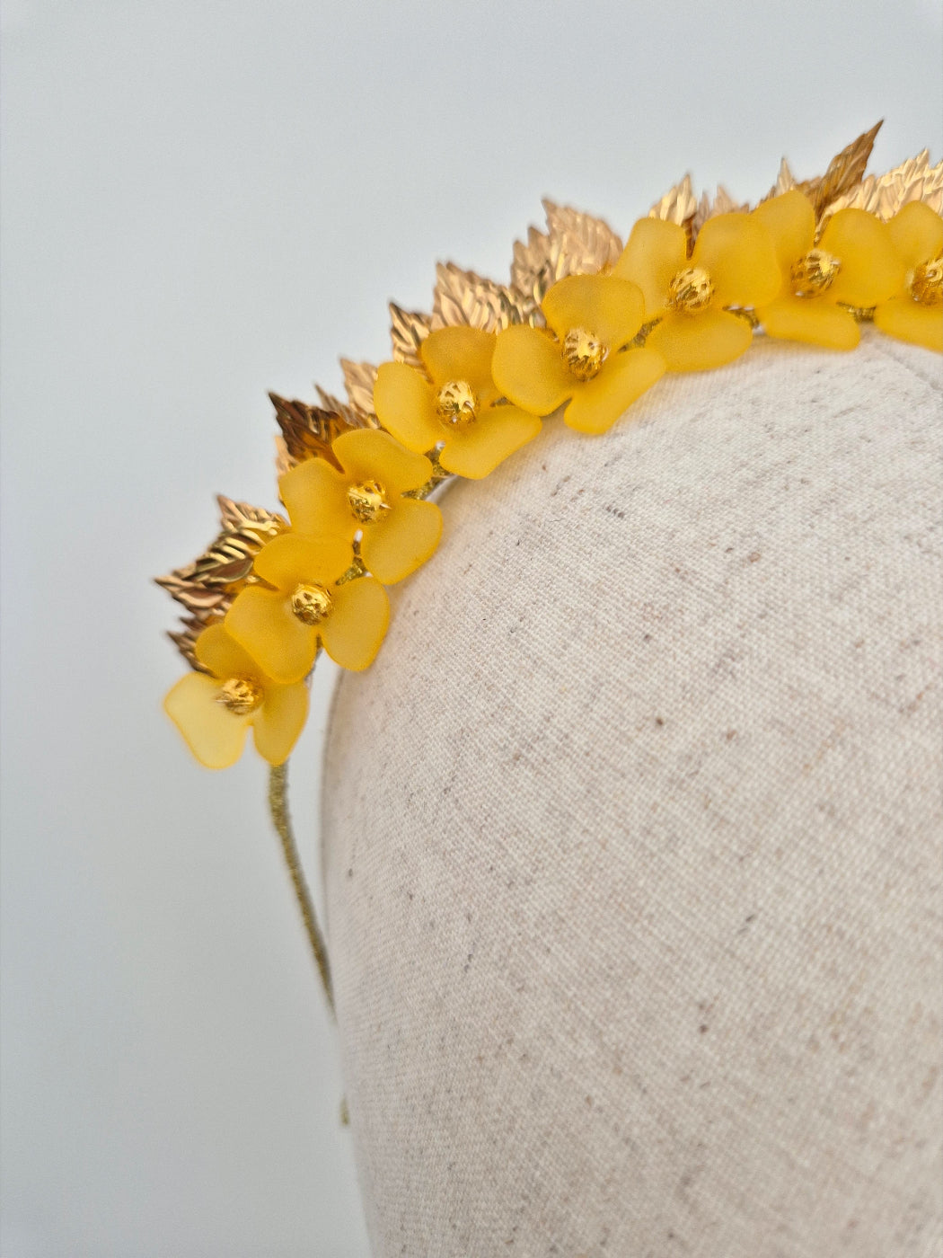 Yellow floral headband with gold accents on a neutral background close up