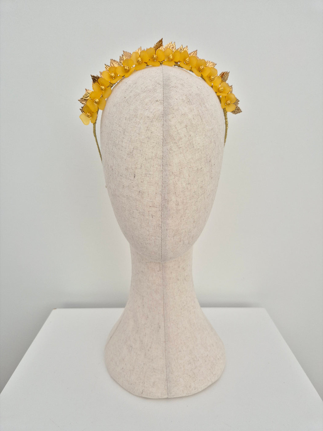 Yellow flower crown on a mannequin head against a white background